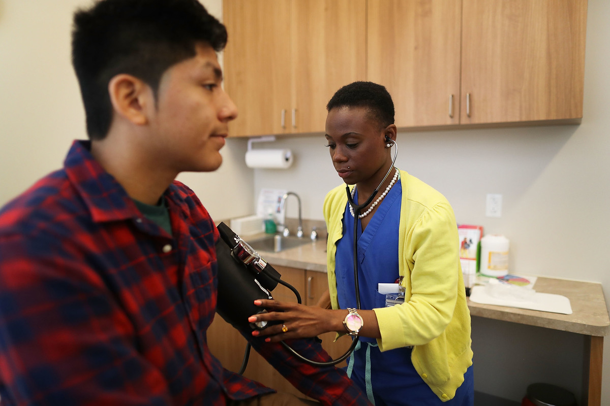 Man has his blood pressure measured by Linda Williams, a medical assistant.