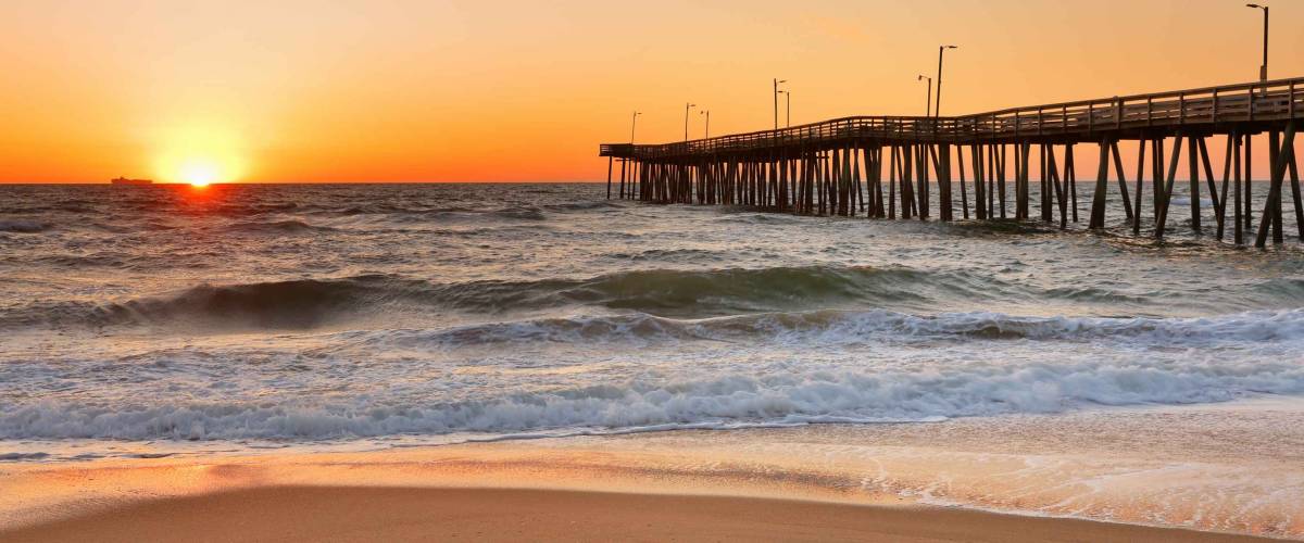 Fishing Pier at Sunrise at Virginia Beach, Virginia, USA. Virginia Beach, a coastal city in southeastern Virginia, lies where the Chesapeake Bay meets the Atlantic Ocean.